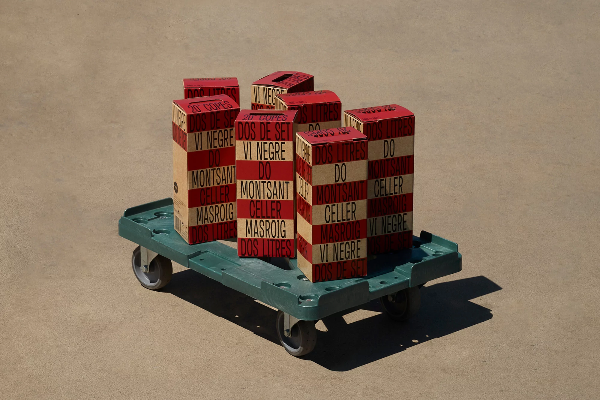 Several boxes labeled 'Vi Negre' are stacked on a green push cart, creating a visually striking display with red and cream colors.