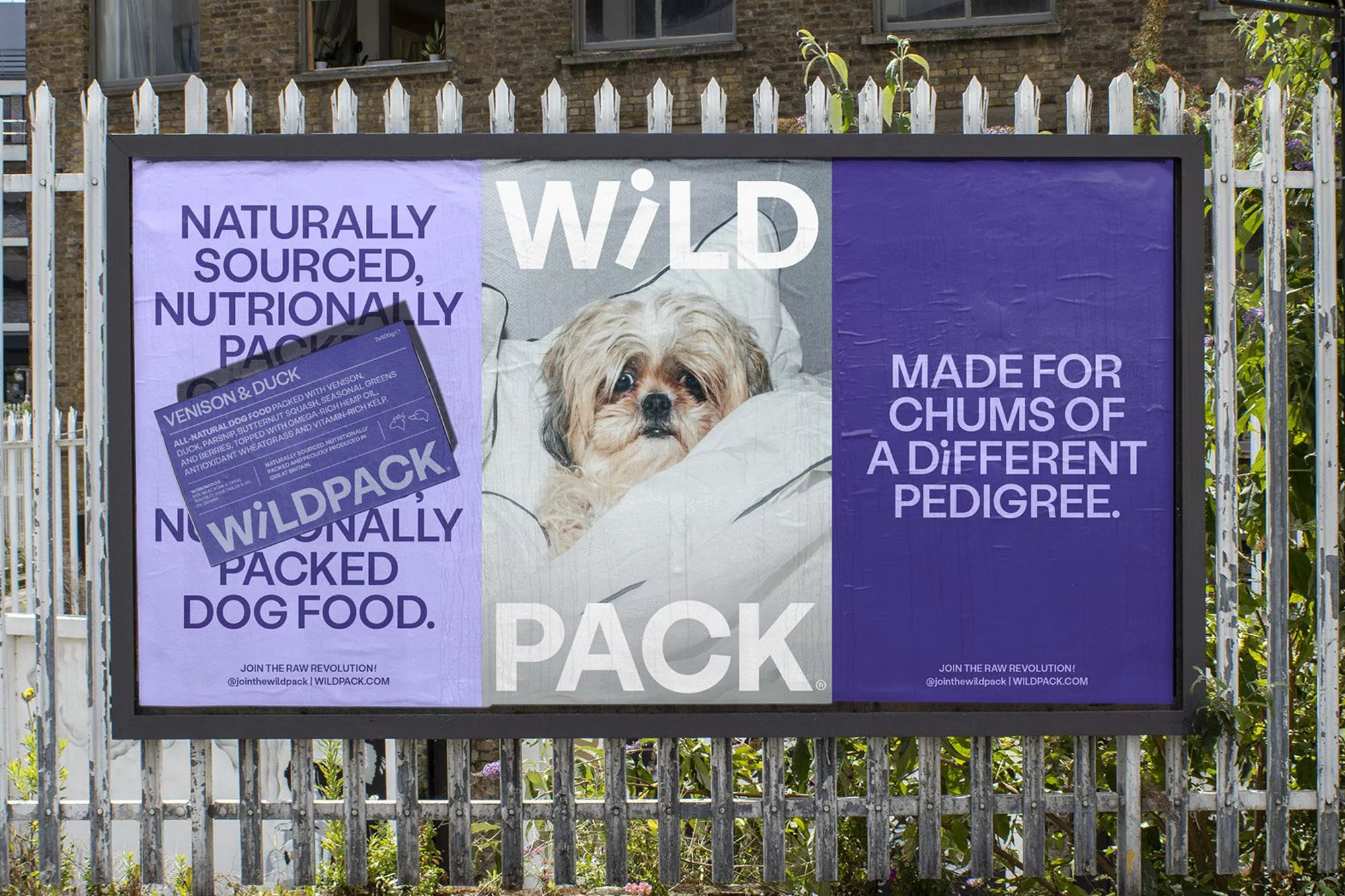 Outdoor billboard ad for Wild Pack dog food featuring a close-up of a Shih Tzu dog in bed and brand messaging on a purple background.