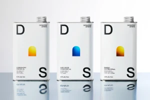 Three rectangular metal spirit tins with white labels and typographic branding reflecting on a surface