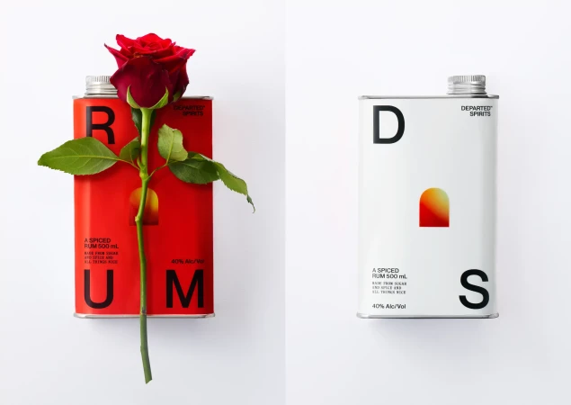 Two metal rum tins against a white background, one red with a fresh red rose laid across it, one white with black typography.