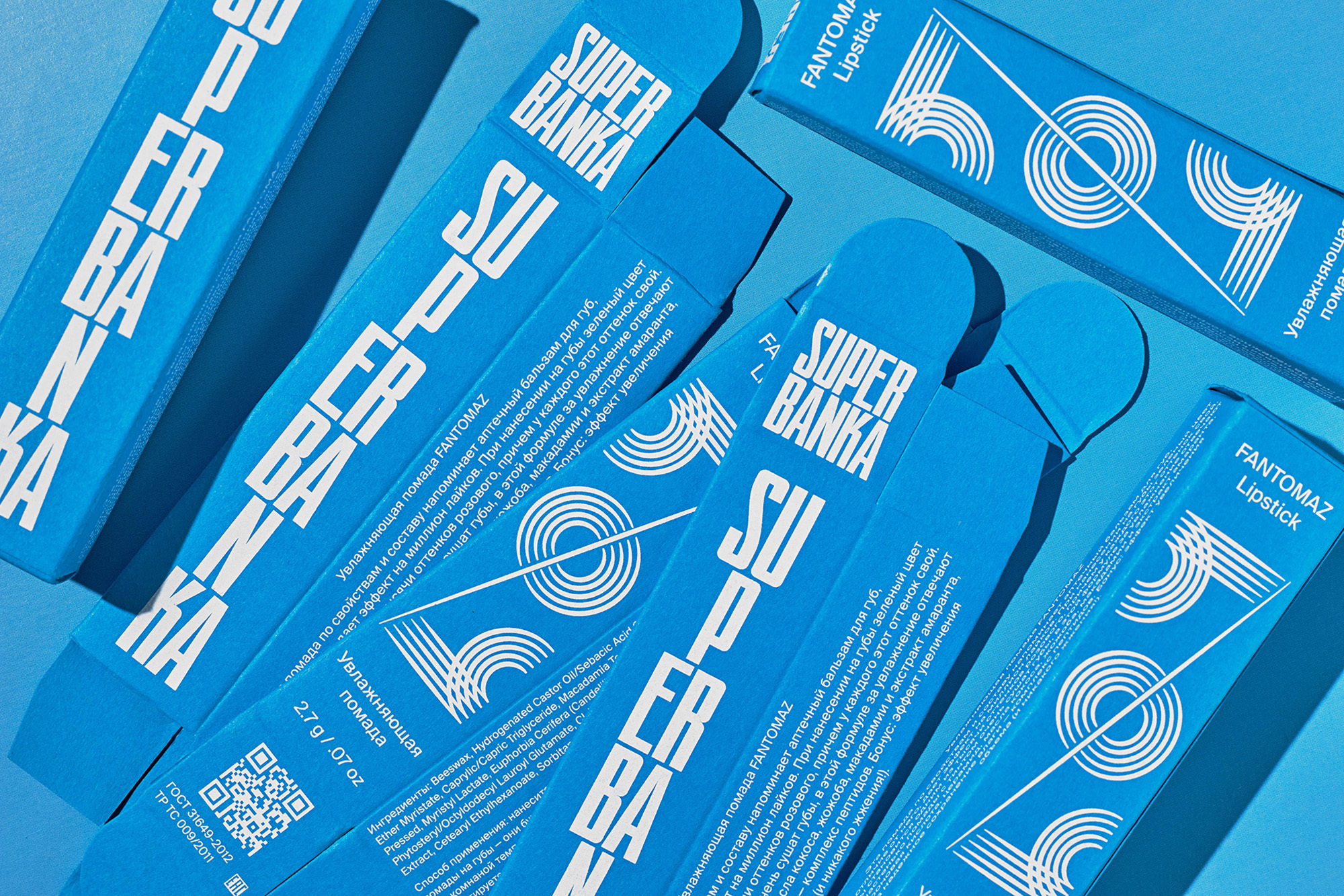 Several blue boxes of Super Banka Fantomaz Lipstick are arranged in a high-angle, close-up shot on a solid blue background.