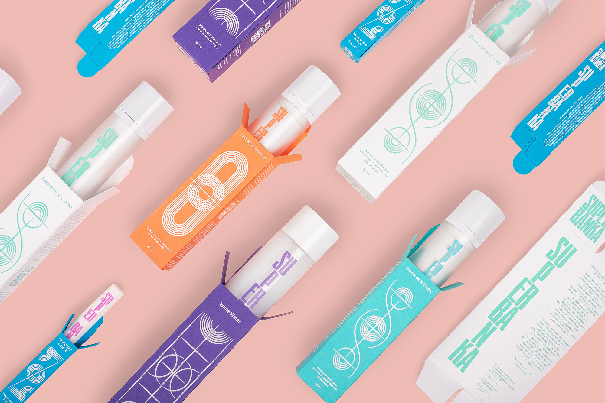 Colorful product packaging of skincare or cosmetic items displayed on a light pink background in a flat lay composition.