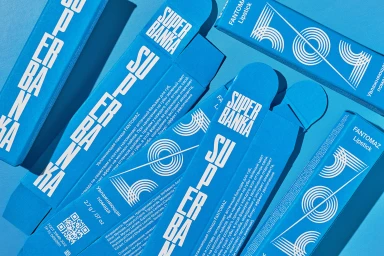 Overhead view of bright blue Superbanka cosmetic packaging boxes with bold white graphic typography and concentric circle designs.
