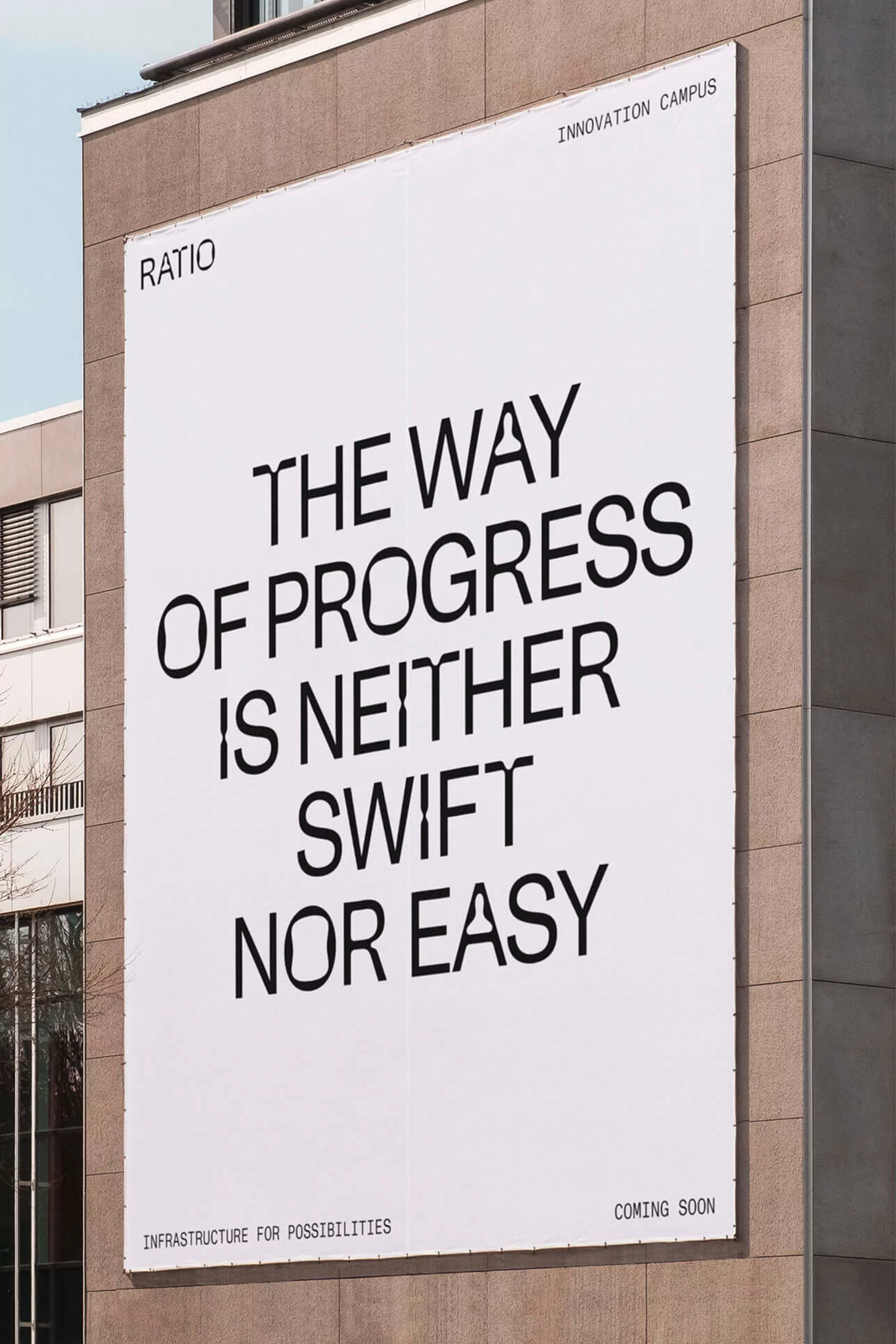 Exterior shot of a building with a large white poster featuring black typography with the text: The way of progress is neither swift nor easy.
