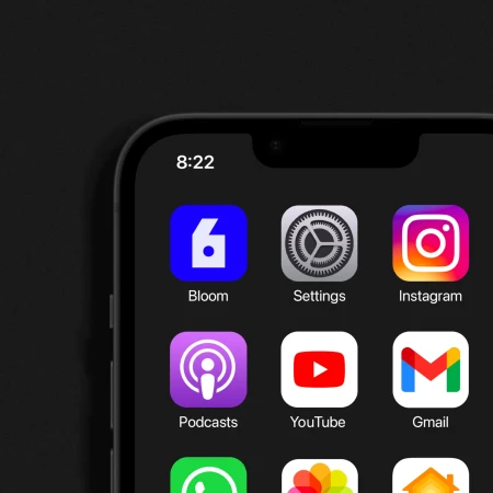 Close-up of a smartphone screen displaying app icons, including Bloom, Settings, Instagram, Podcasts, YouTube, and Gmail, on a dark background.