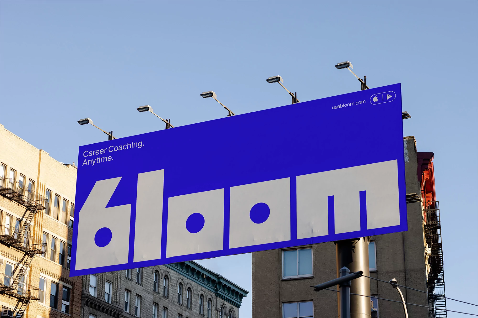 Large blue billboard featuring the word 'bloom' in white, set against a blue sky and urban buildings with architectural details.