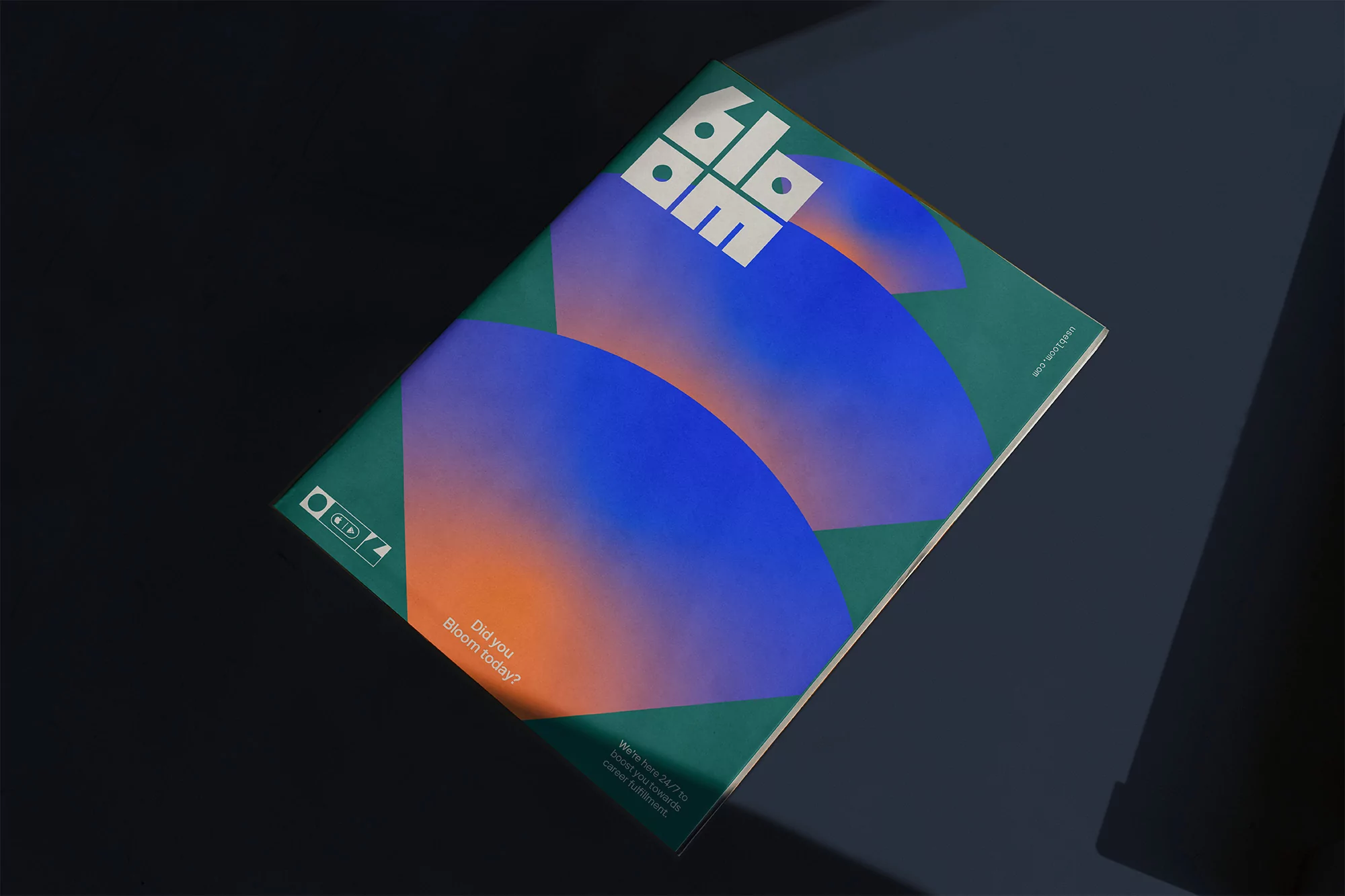 A magazine cover displays blue and orange gradient circles on a green background, angled on a dark gray surface with shadows.