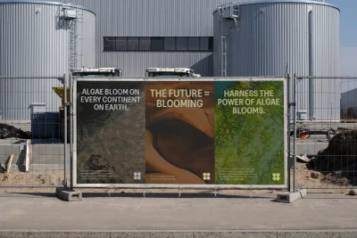 Brilliant Planet brand identity advertising banner mounted on a chain-link fence in front of large industrial tanks