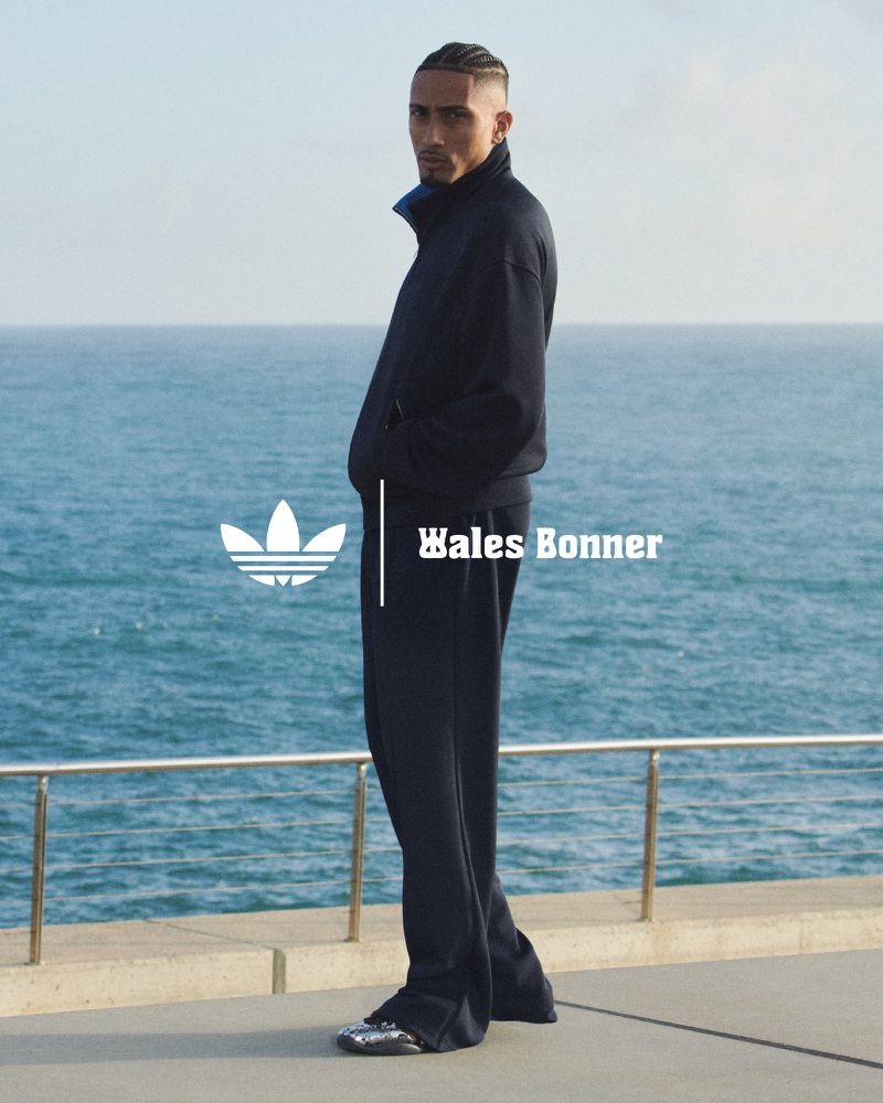 Athletic man in Wales Bonner tracksuit by ocean. Adidas logo and brand name are displayed. Fashion, fitness, and sport concept.