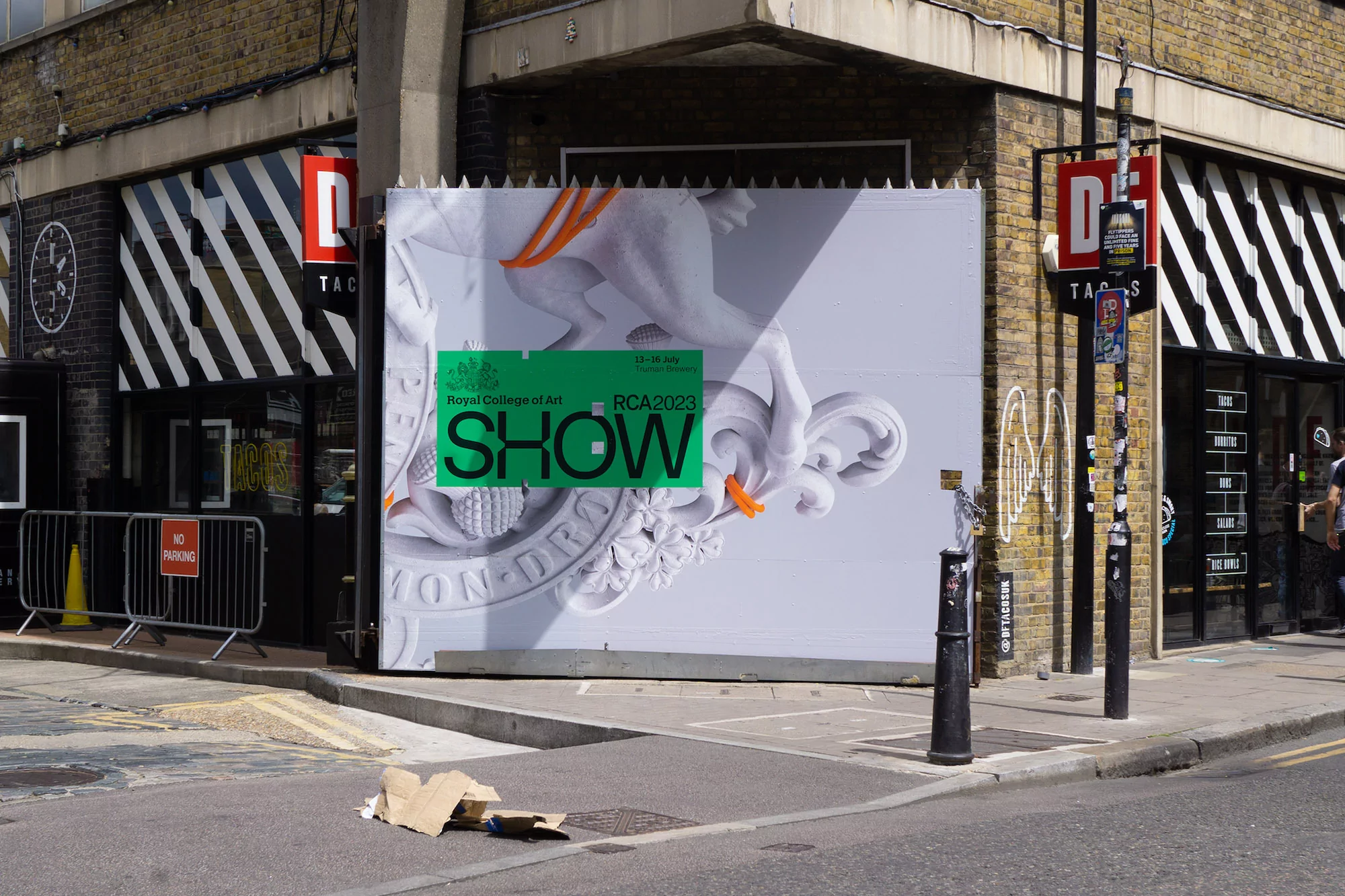 Outdoor shot of an art exhibition advertisement featuring a white sculpture design on a building facade in a neutral-toned urban setting.