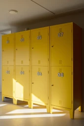 Four vibrant yellow lockers numbered zero one through zero eight standing in a bright indoor room with sunlight streaming across the floor