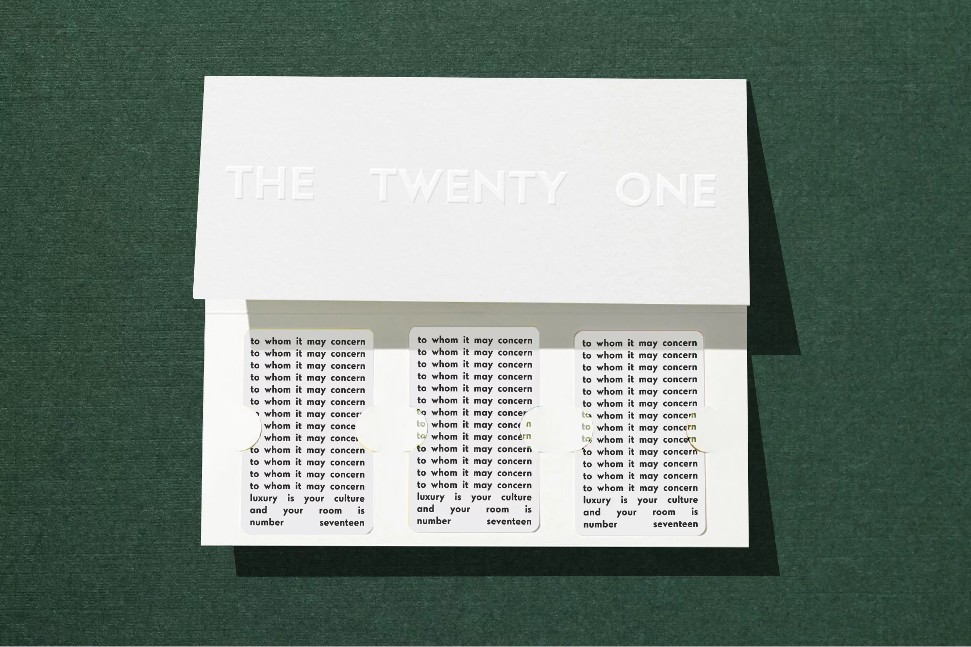 Close-up of a white card with embossed text and printed labels, showcasing a minimalist aesthetic on a green surface.