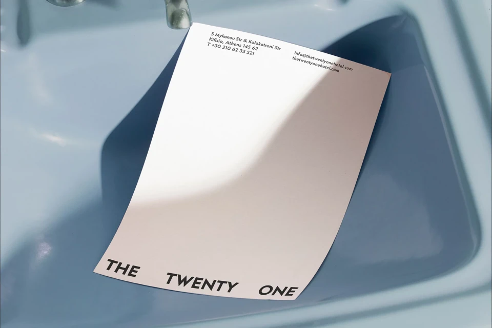 Promotional flyer from The Twenty One Hotel on blue surface. The flyer features the hotel's name and contact information.