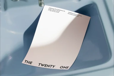 White letterhead placed inside a glossy blue ceramic washbasin with visible typography and contact information