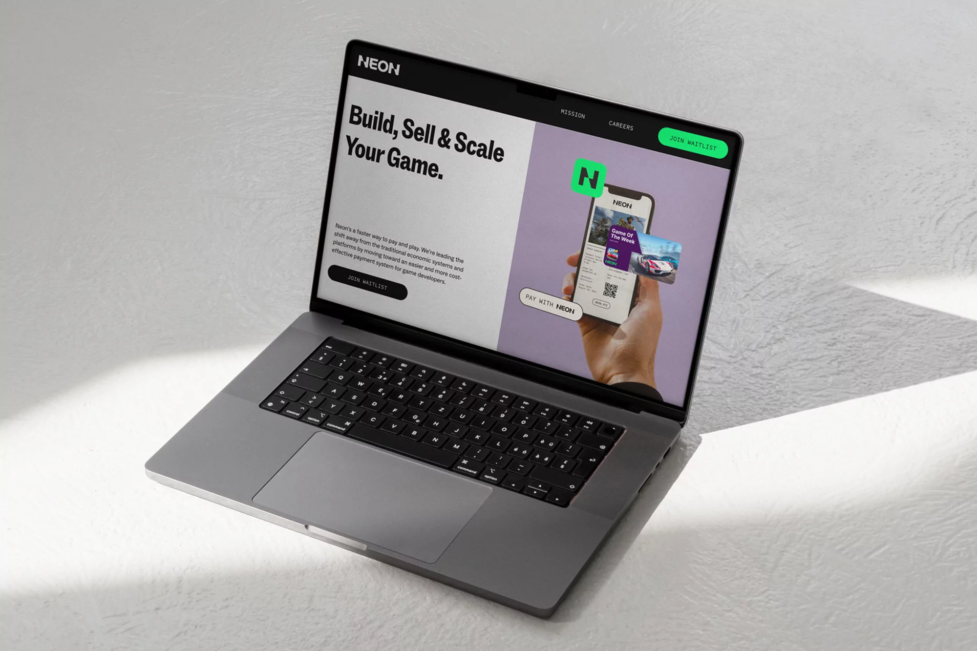 Laptop displaying the Neon website with a mobile interface in hand, promoting game building, selling, and scaling.
