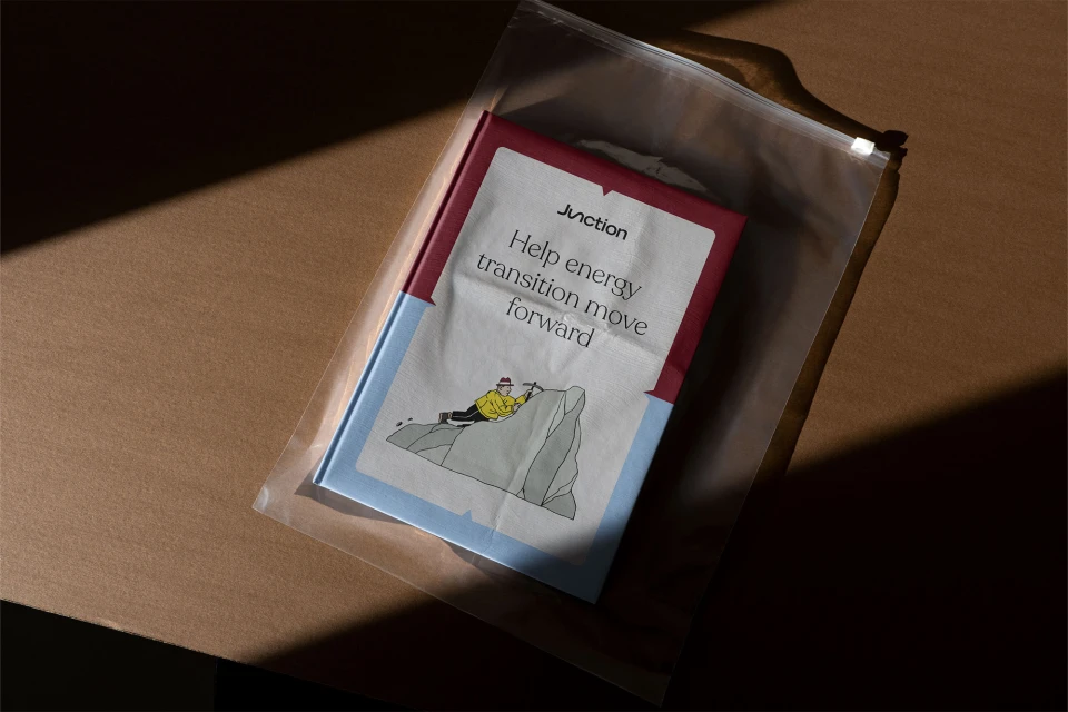 Junction-branded booklet, featuring an illustration of a climber scaling a gray rock, enclosed in a clear plastic zip-lock bag on brown surface.