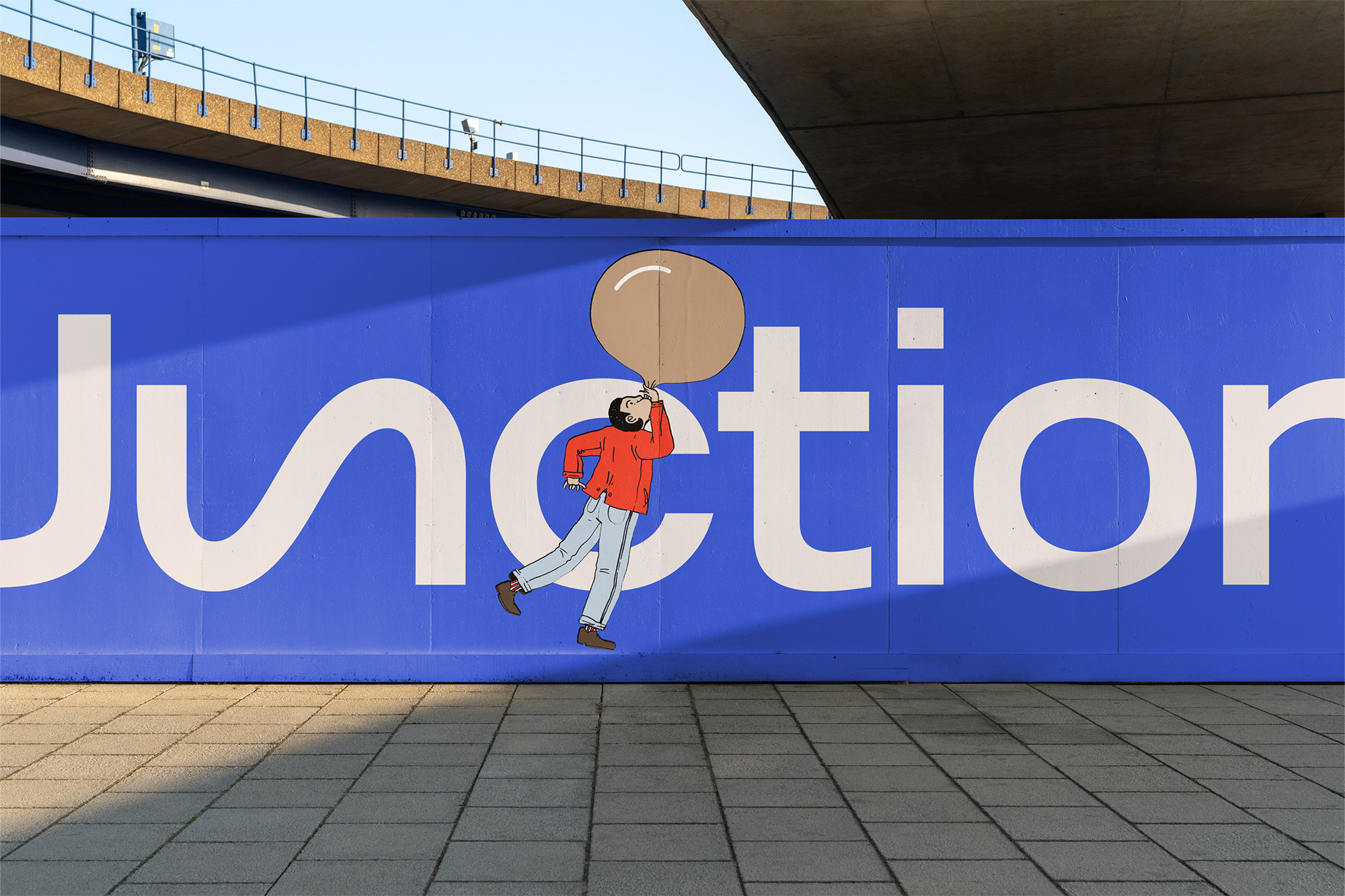 Illustration of a man blowing a bubble next to the large Junction text on a building wall under an overpass, on a tiled surface.