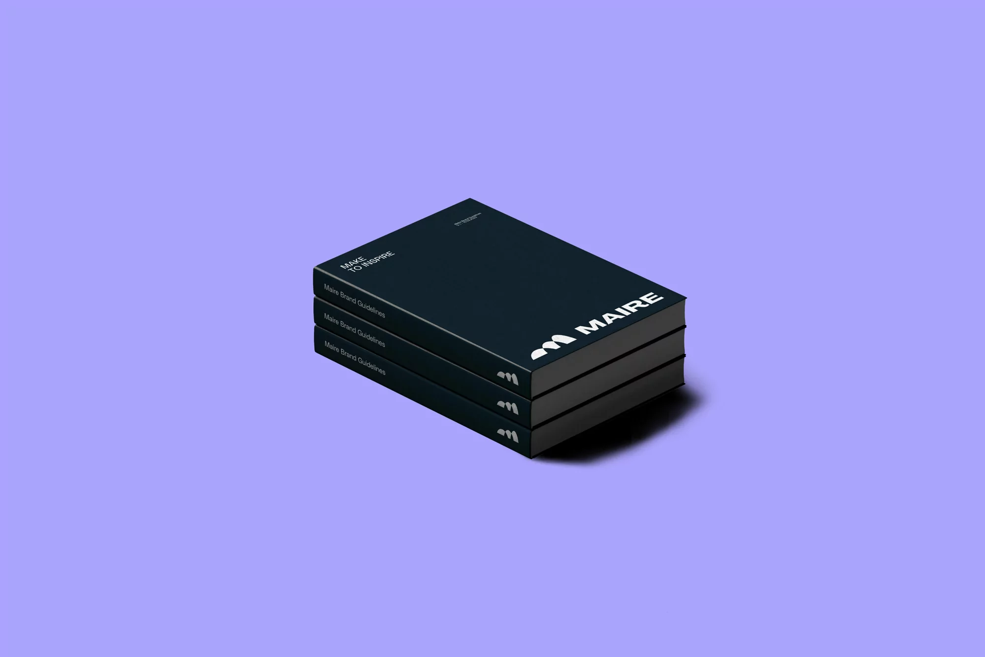 Three stacked books with the brand name 'MAIRE' on the cover, set against a soft purple backdrop, creating a minimalistic composition.