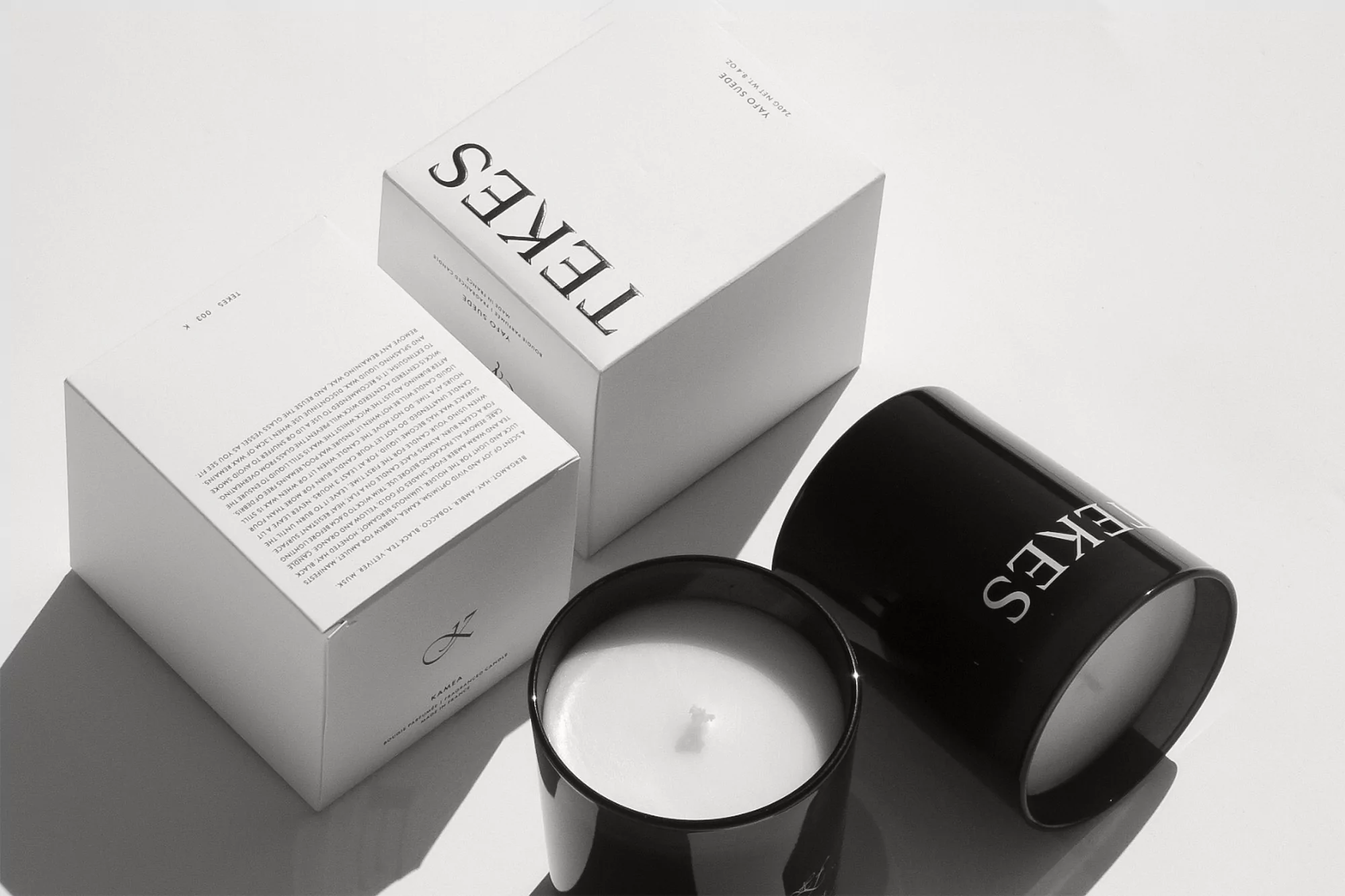 Two white boxes and two black candles, minimalist style, studio lighting, with crisp, clean presentation against a bright backdrop.