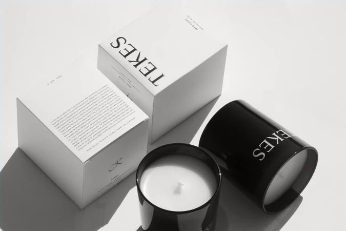 Two white boxes and two black candles, minimalist style, studio lighting, with crisp, clean presentation against a bright backdrop.