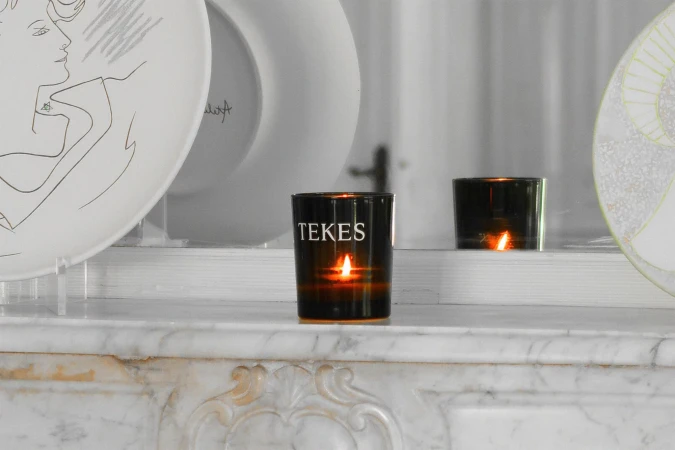 Two black glass candle holders with burning tea lights sit on a white marble surface, illuminated by the flickering candlelight.