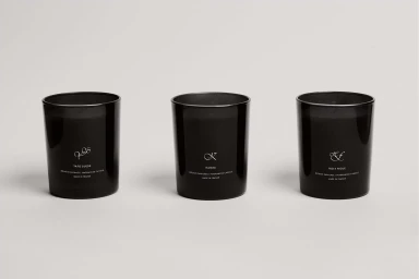 Three black glass scented candles arranged in a row on a minimal neutral studio background for TEKES brand identity