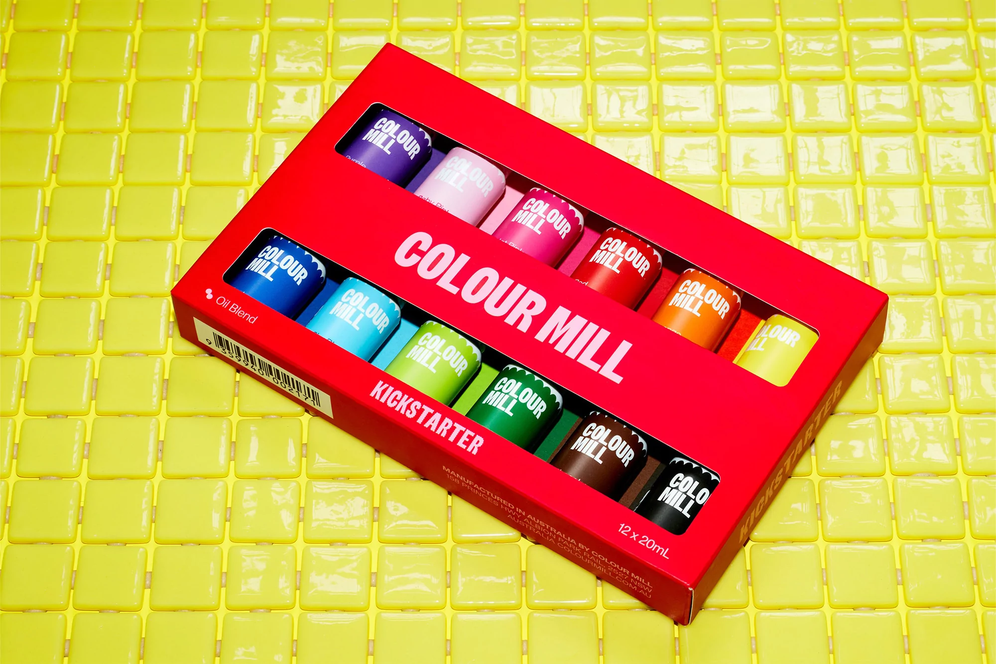 Colour Mill food coloring set in a red box on yellow tile. Colour Mill oil blend in a variety of colors for baking and confectionery.