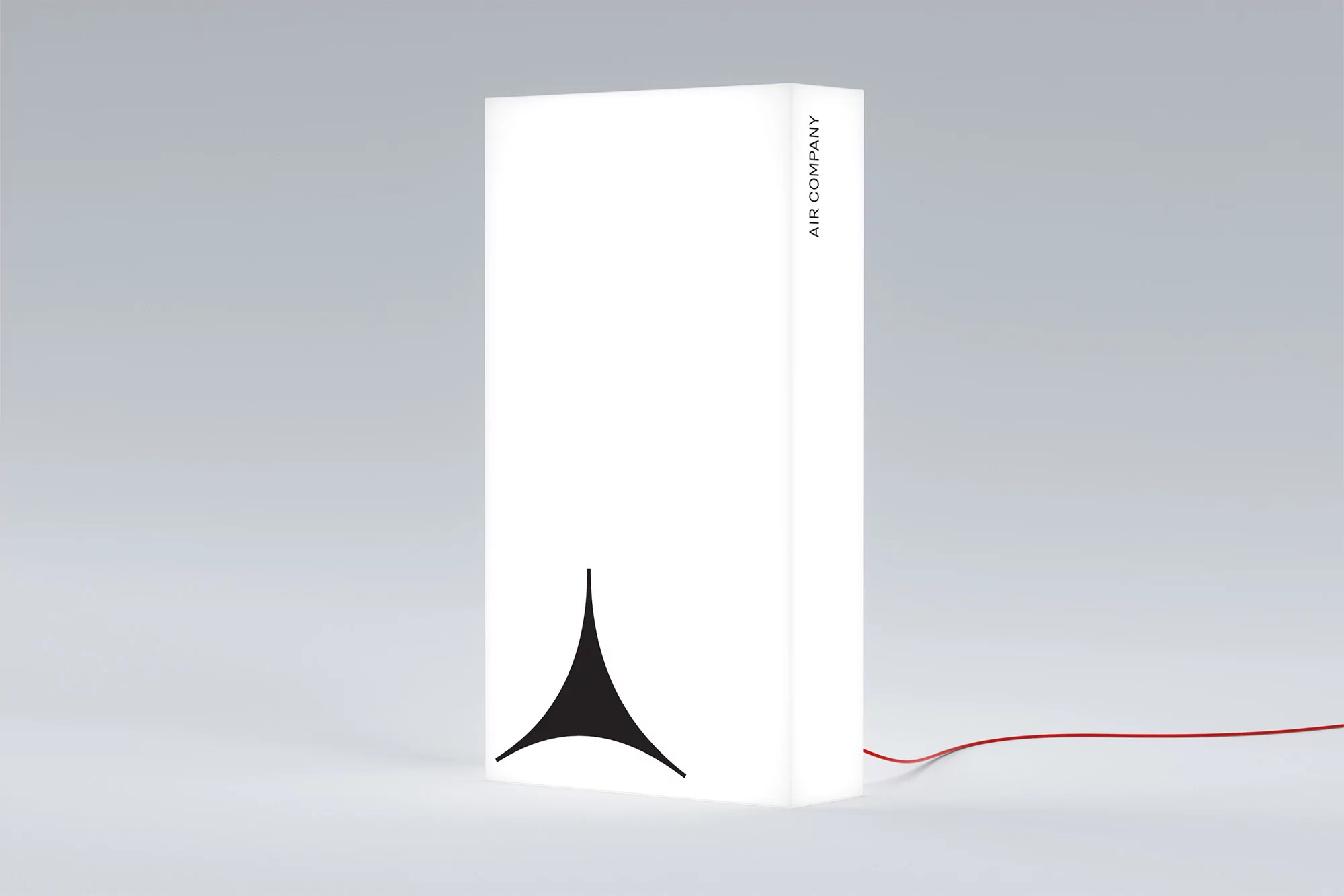 Modern white lamp with a black logo and thin red cord on a light gray background, creating a clean and minimalist aesthetic.