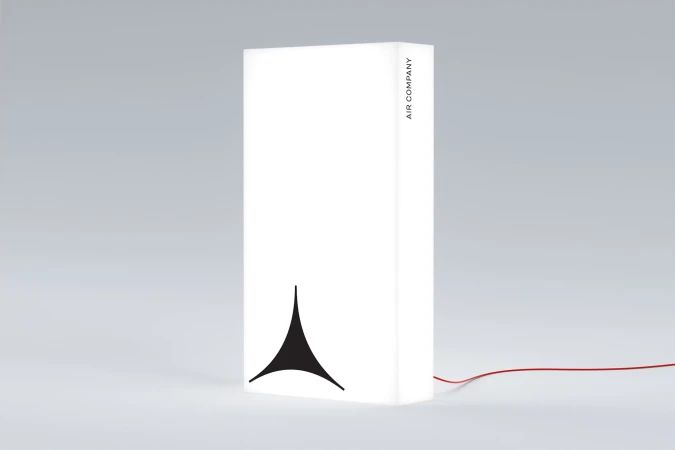 Modern white lamp with a black logo and thin red cord on a light gray background, creating a clean and minimalist aesthetic.