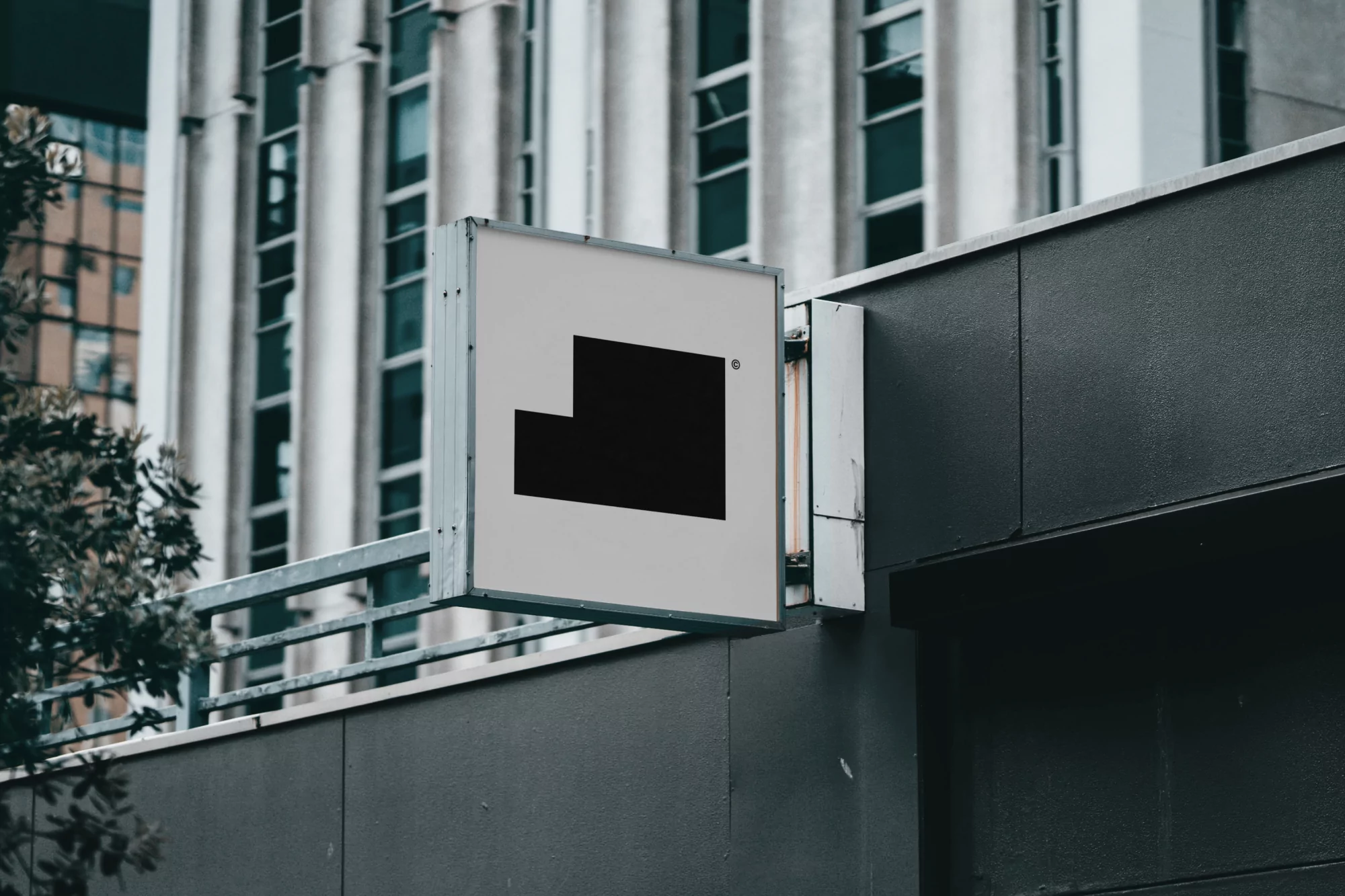 Abstract black logo sign on gray wall of building. Modern architectural design with geometric black shape against a city building backdrop.