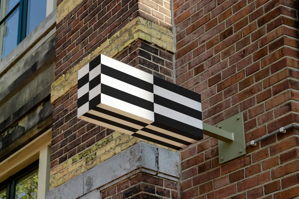 Exterior architectural detail featuring a black-and-white striped rectangular sign mounted on a brick wall, adding visual interest to the building.