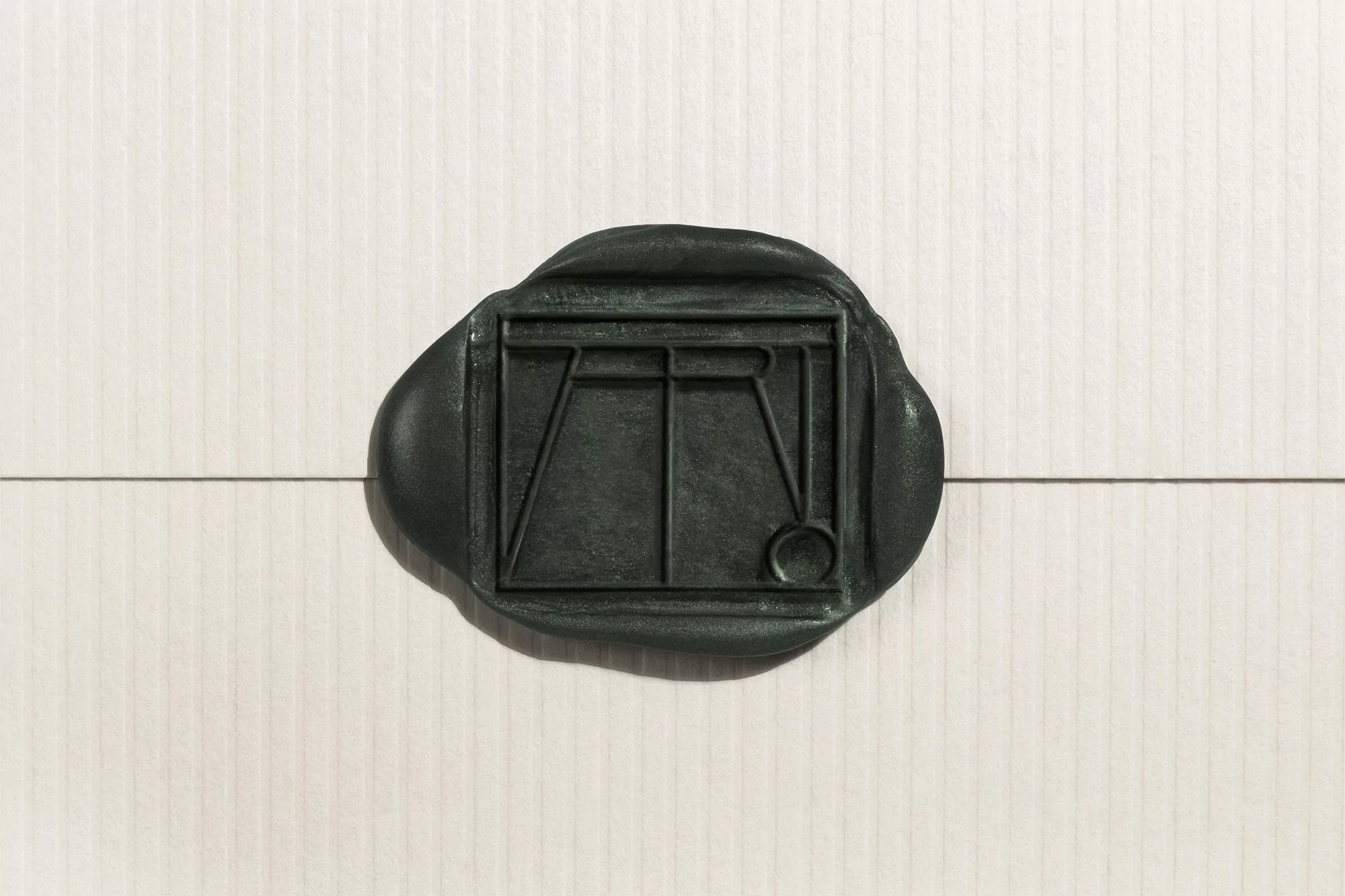 A close-up photograph features a dark green wax seal embossed with a geometric design, set against a white, vertically ribbed background.
