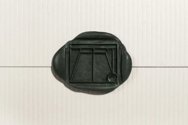 Dark green wax seal stamped with Atrio logo on textured white paper background