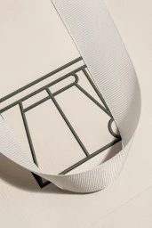 Close-up of a white textured paper bag with dark green debossed logo and white grosgrain ribbon handle.