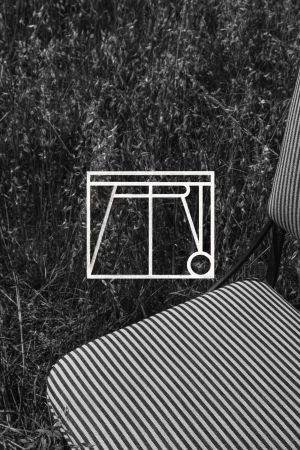 Black and white image of a striped chair outdoors featuring a geometric brand logo overlay