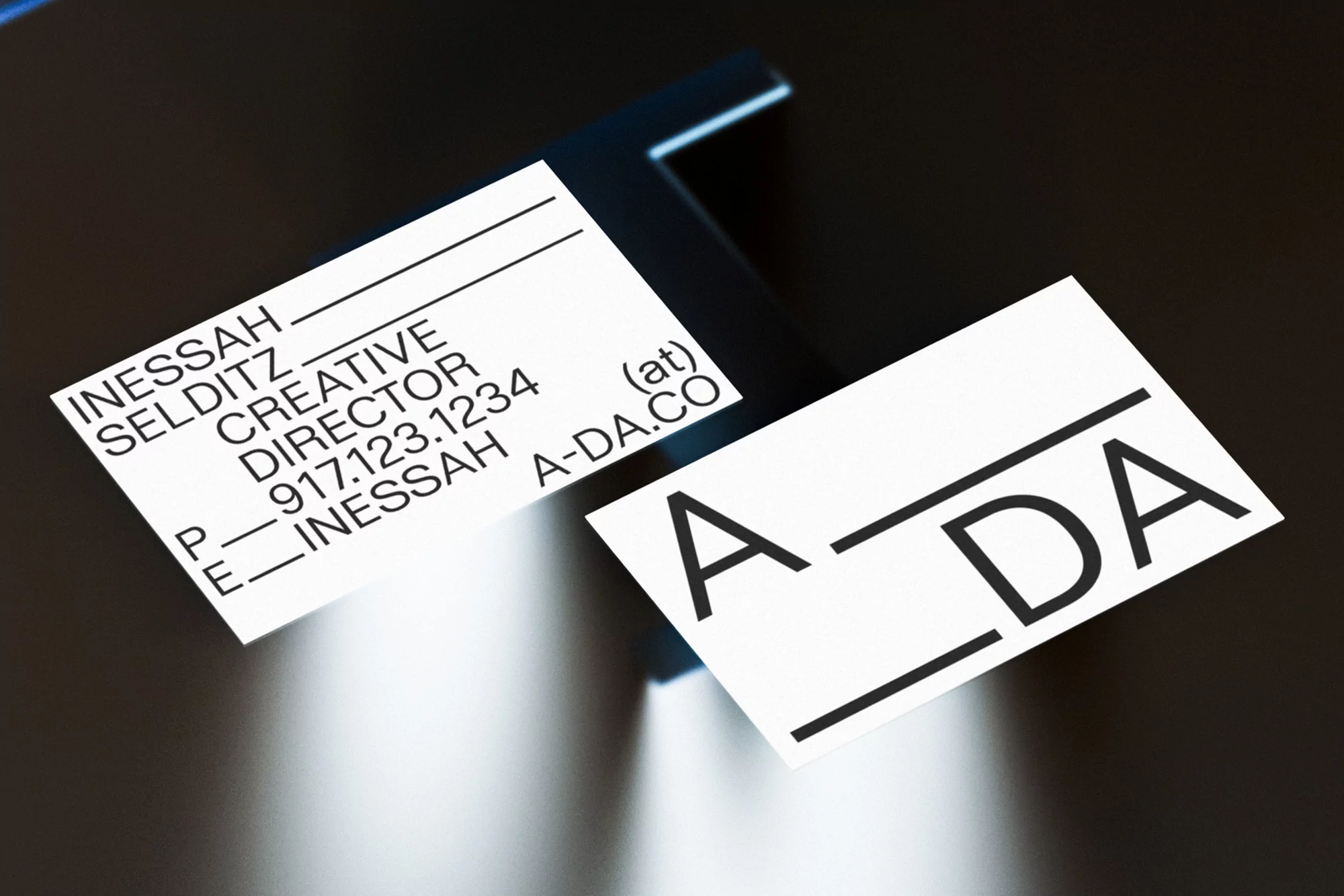 Two printed business cards with typography on a dark reflective surface