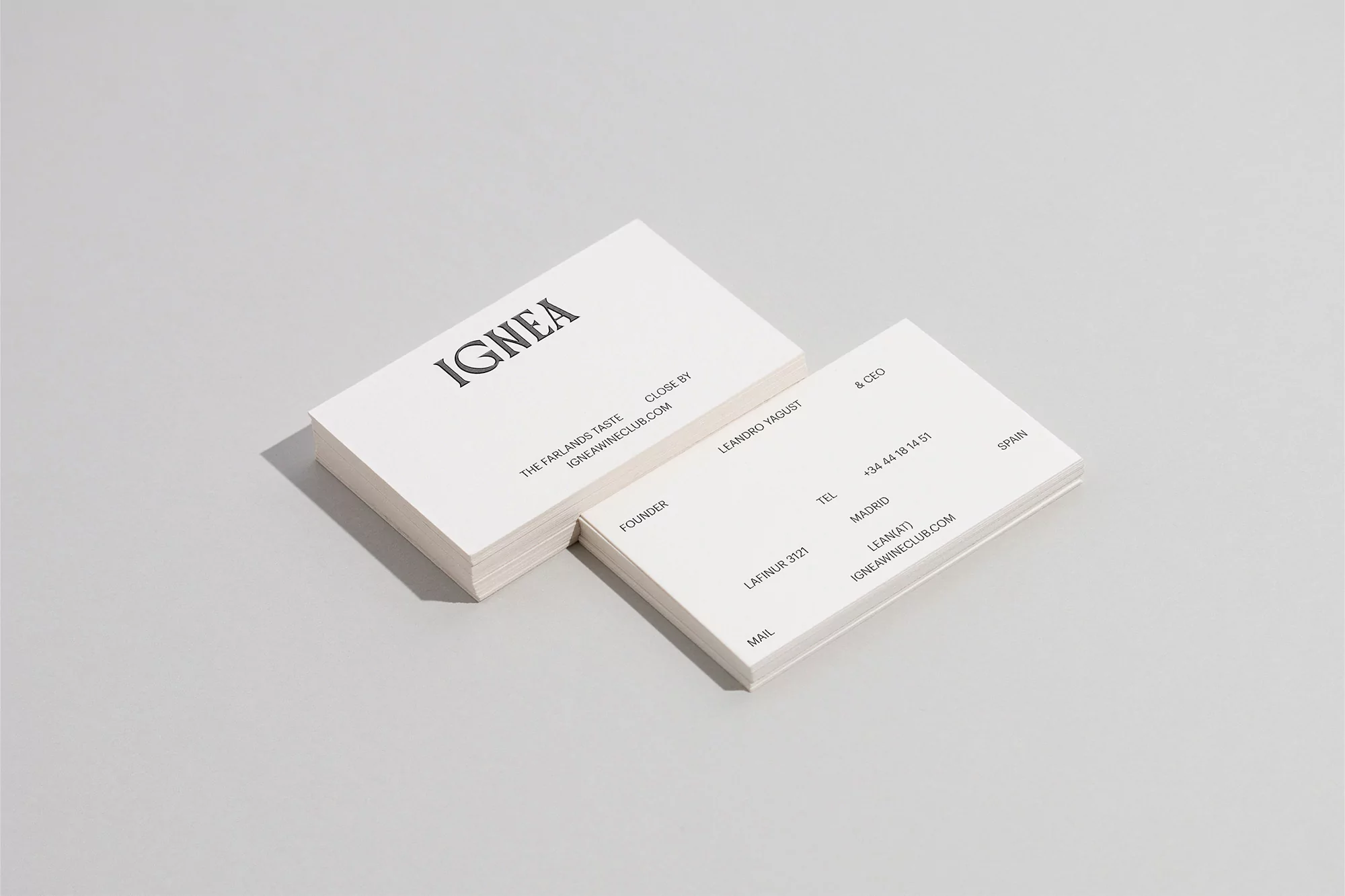Two stacks of white business cards angled on a light gray surface, featuring black serif typography and clean, minimalist design.