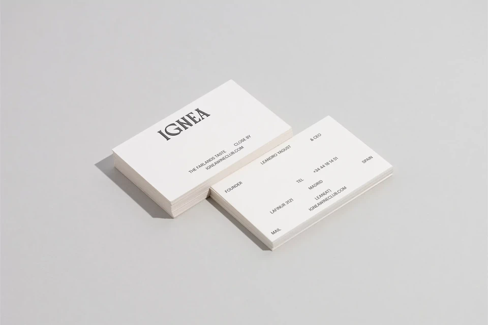 Two stacks of white business cards angled on a light gray surface, featuring black serif typography and clean, minimalist design.