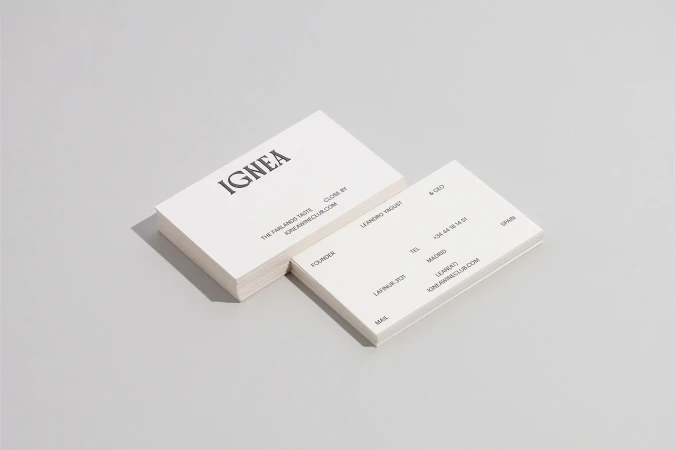 Two stacks of white business cards angled on a light gray surface, featuring black serif typography and clean, minimalist design.