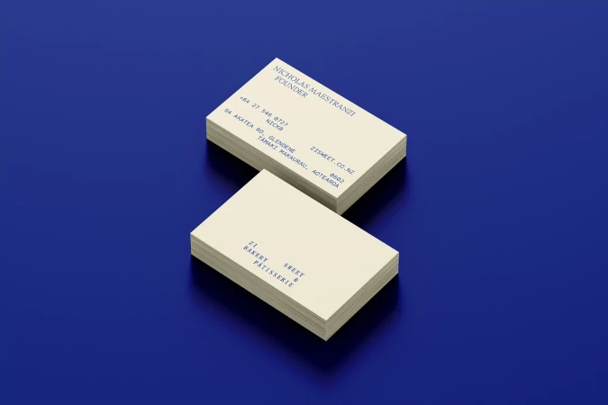 Stacks of cream-colored business cards with dark blue text on a royal blue background, creating a minimalist and professional presentation.