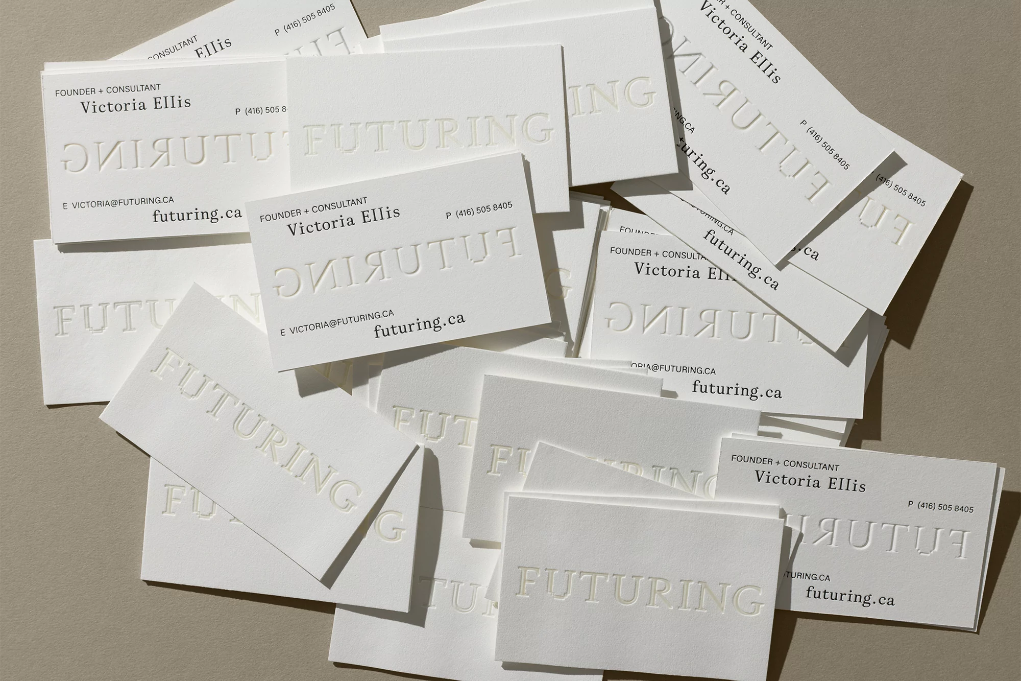 Scattered white business cards featuring embossed typography and the text FUTURING against a neutral textured background