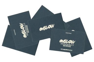 Scattered dark grey business cards featuring cream-colored typography on a plain white background