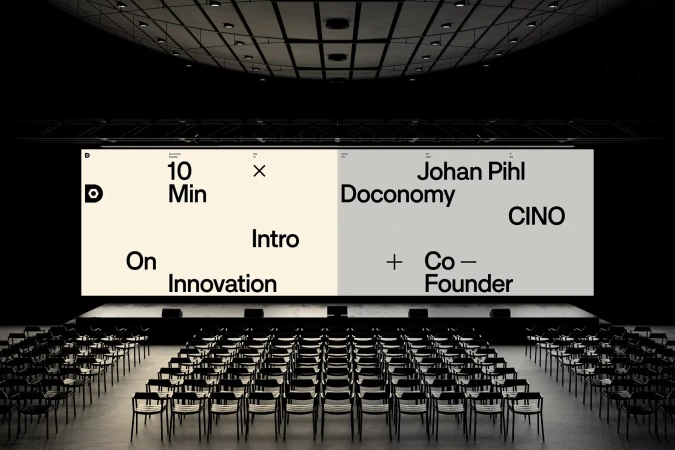 Empty auditorium with rows of chairs facing a large screen displaying presentation slides with business-related content, conference setting.