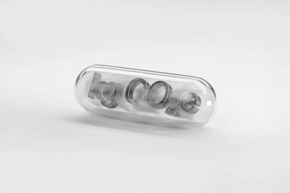 Pill capsule with 'kg CO2e' inside, representing carbon footprint reduction, sitting on a white surface. Clean, studio shot.
