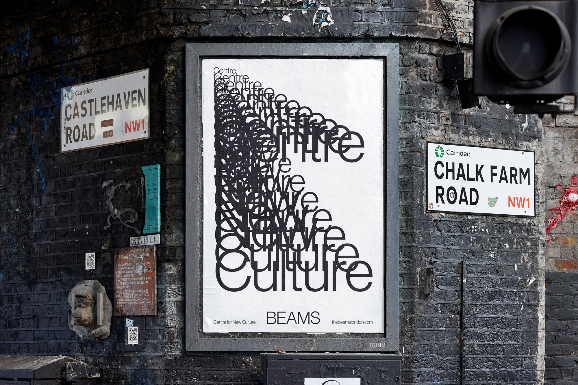 Outdoor advertising poster with the repeated text 'Culture' displayed on black brick wall in Camden, London, next to road signs.