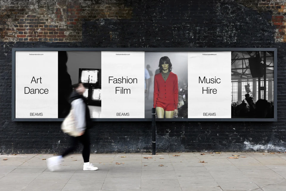Advertisment billboard on city street featuring imagery for art, fashion, and music services by BEAMS, with a blurred pedestrian.
