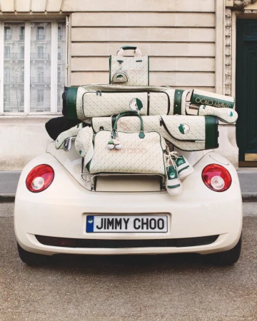 Jimmy Choo branded golf bags and accessories are stacked on the back of a vintage car with a building in the background.