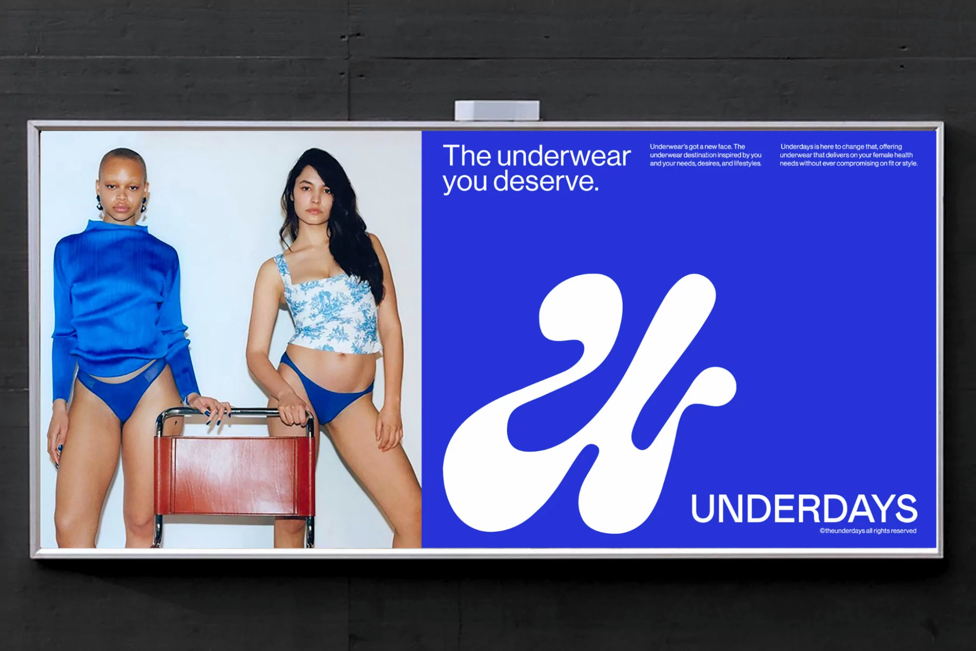 Billboard advertisement featuring two women in underwear for the brand Underdays, set against a blue and white graphic background.