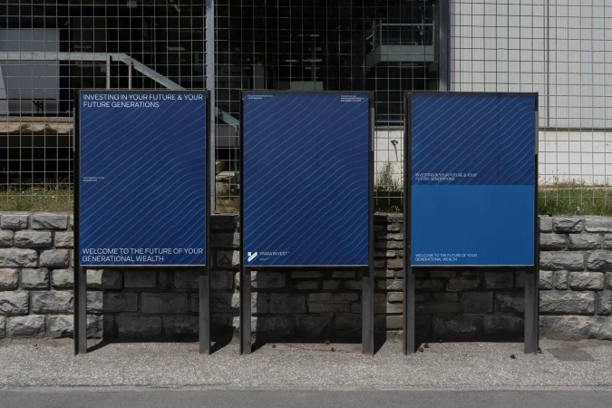 Three advertising signs are placed on a stone wall, featuring a blue and white pattern and the text, “Investing in your future”.