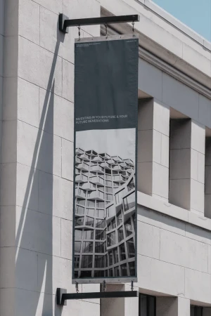 Vertical dark banner signage hanging from a classical stone building exterior with architectural detail